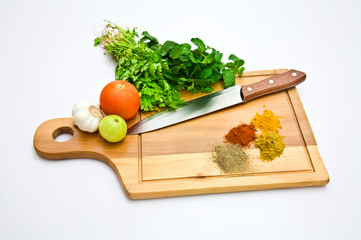 Food and cooking background. Wooden cutting board with chopped paprika and chef knife. Zucchini, raw vegetables, spices and ingredients for cooking vegan Asian dishes with ginger, garlic, soy sauce, top view