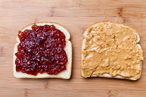 Open Face Peanut Butter and Jelly Sandwich Simple peanut butter and jelly sandwich with strawberry jam and chunky peanut butter on white bread, separated and placed on a bamboo cutting board with soft natural window light. peanut butter and jelly sandwich stock pictures, royalty-free photos & images