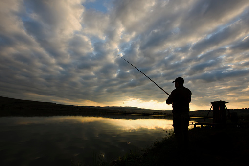 man silhouette at sunrise fishing.