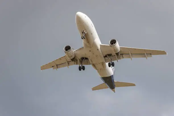 Photo of Flying airplane from below. Grey background.