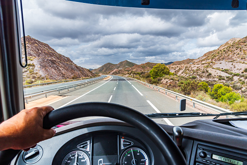 View from the driving position of a truck of the highway and a mountainous landscape.