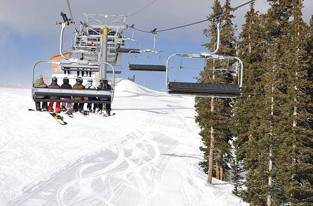 Skiiers and Snowboarders Riding Up a Ski Lift A group of young skiiers riding up the chair lift in Keystone, Colorado on winter vacation. summit county stock pictures, royalty-free photos & images