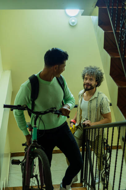 istock Gay couple chat while climbing the stairs and enjoy a conversation while loading the bicycle they use to get around 1684515085