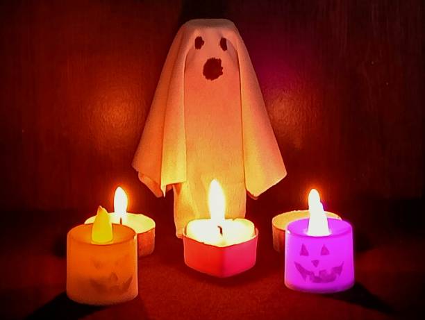 istock White-robed ghost, Pumpkin and candles. 1684517877