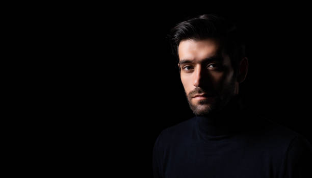 istock Pensive thinking handsome young beared man portrait Attractive bearded confident guy planning something looking at blank space Smart man thinking in the dark room Confident Cool man looking at camera 1684522289