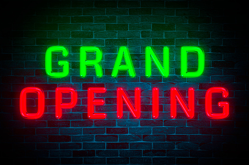 Grand Opening neon banner on brick wall background.