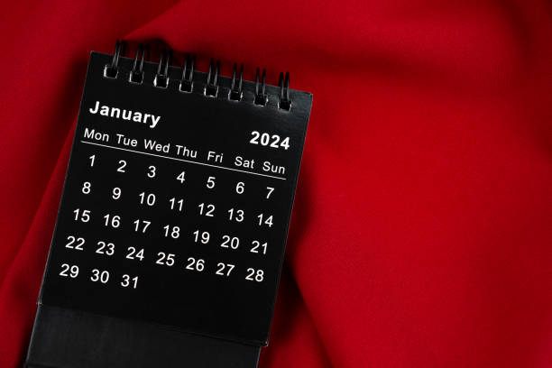 istock The January 2024 Black spiral desktop calendar on red textile. 1684531574