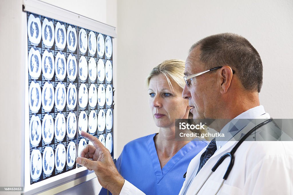 Doctor And Nurse Consulting On X-Ray XXXL. Doctor and nurse examing an MRI scan on an x-ray lightbox. Adult Stock Photo