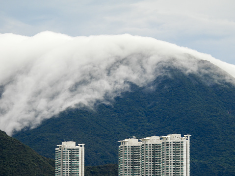 Clouds cover the top of the mountain on Lantau Island.  In the foreground are residential buildings.  This image was taken from Hong Kong International Airport on an overcast afternoon on 12 September 2023.