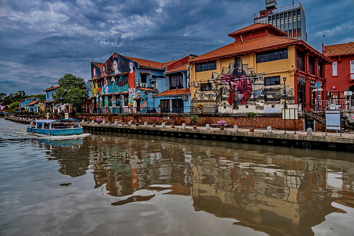 Malacca, Malaysia - August 14, 2023 : Tour boat crossing the Malacca River along the historical buildings with the beautiful murals. Malacca City (also spelled Melaka) is the oldest Malaysian city on the Straits of Malacca. Noted for its unique history, it has been listed as a UNESCO World Heritage Site since 2008.