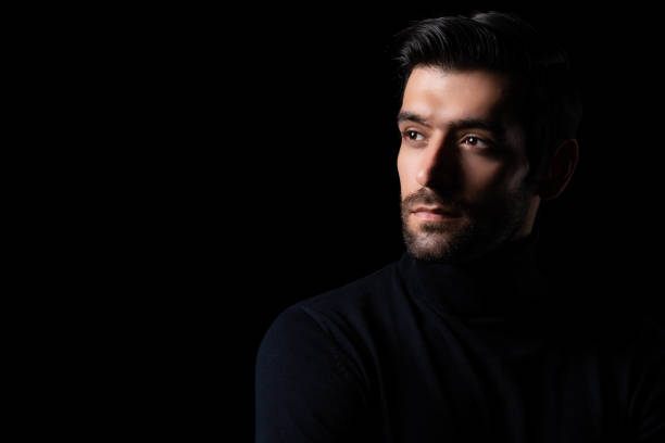 istock Pensive thinking handsome young beared man portrait Attractive bearded confident guy planning something looking at blank space Smart man thinking in the dark room Cool man look smart and good looking 1684554060