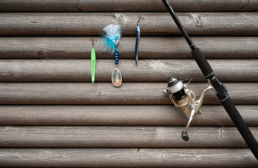 spinning wheel and rod with coourful lures hanging on a grey  wall of stocks