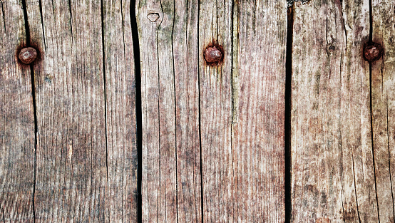 Rustic old weathered rotten cracked hardwood decking planks fixed with rusty screws, high resolution background texture stock image.