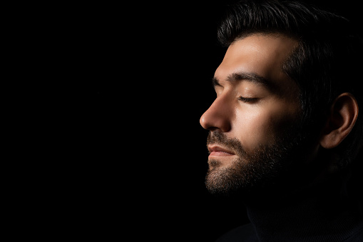 Close up face Caucasian handsome man isolated on black background Handsome man close eyes in studio on dark background Attractive Bearded guy thinking something in the dark room