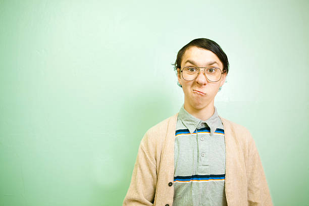 Teenage Nerdy Guy with green wall copy space A super nerdy male teenager makes a funny face at the camera. Copy space on a green wall background. nerd teenager stock pictures, royalty-free photos & images