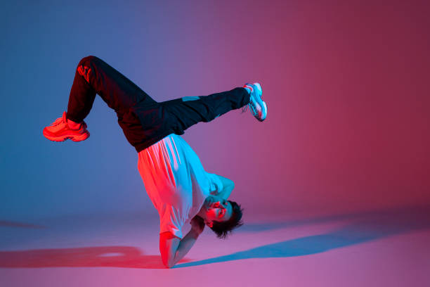 istock dancer doing acrobatic trick and dancing breakdance in neon red and blue lighting, young guy stands on his hands 1684671551
