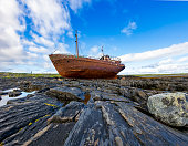 Stuck old fishing schooner on the rocky coast of the Barents Sea, Rybachy Peninsula. The old ship is covered with rust.