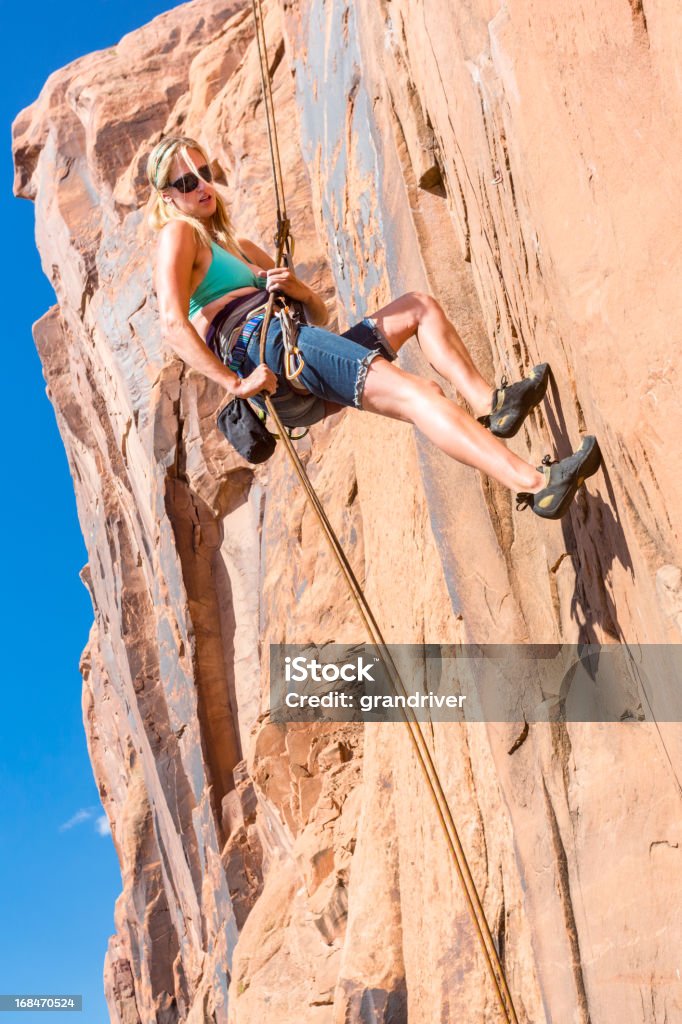 Young Woman Rock Climber on a sandstone cliff Young Woman Rock Climber at Wall Street near Moab Utah Achievement Stock Photo