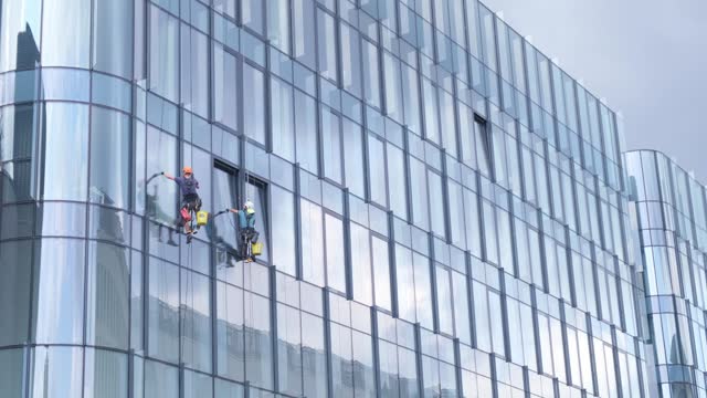 Men wash windows on a glass skyscraper in New York. Dangerous work at height