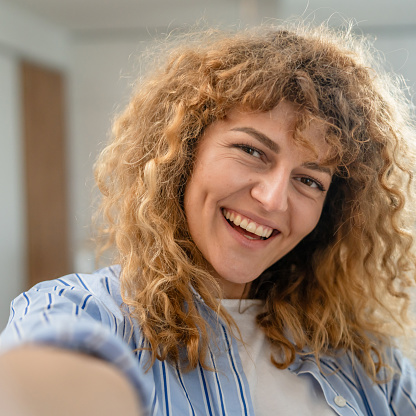 Portrait of one adult caucasian woman at home happy smile curly hair
