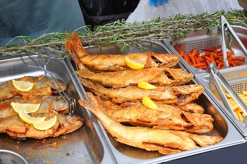 large fried fish in restaurant tray with some lemon slices