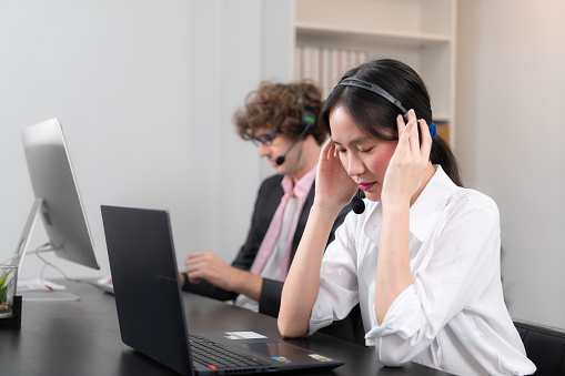 Group of business people wearing headset working actively in office. Call center, telemarketing, customer support agent provide service on telephone video conference call.