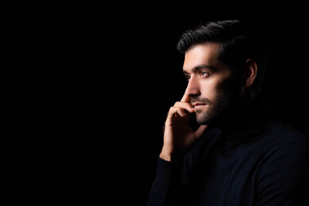 istock Pensive thinking handsome young beared man portrait Attractive bearded confident guy planning something looking at blank space Smart man thinking in the dark room Cool man get good idea imagination 1684713989