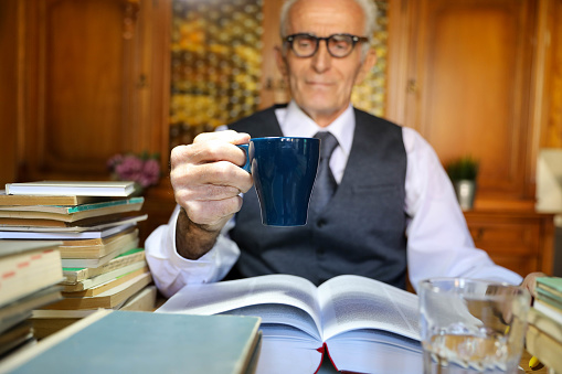 Senior businessman in the office with a cup of coffee in his hand.