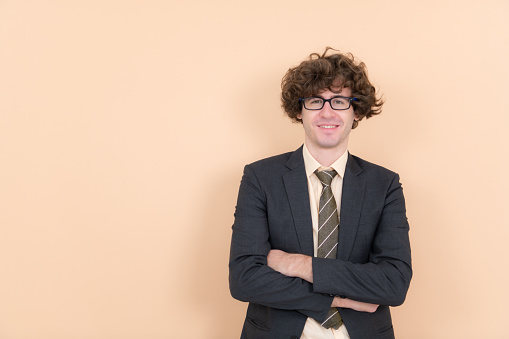 Portrait of a handsome young man with curly hair on a beige background
