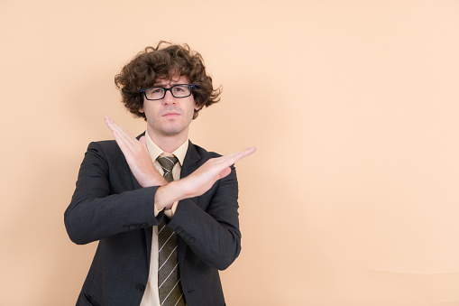 Portrait of a handsome young man with curly hair on a beige background