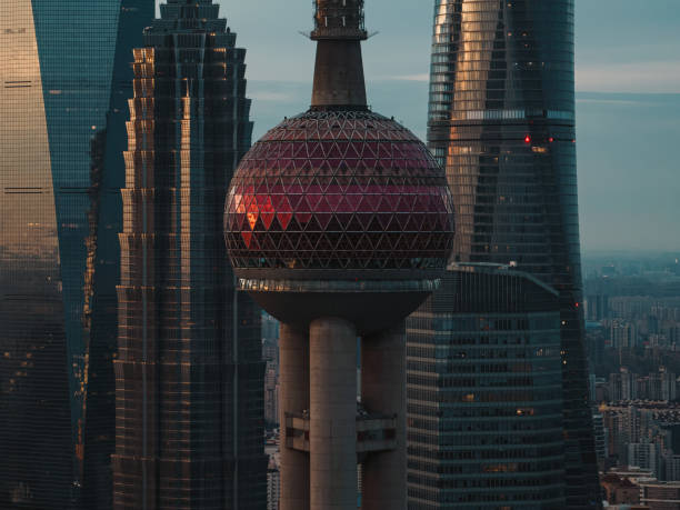Aerial view of the Oriental Pearl Tower in Shanghai with intricate patterns and urban surroundings in the morning light.