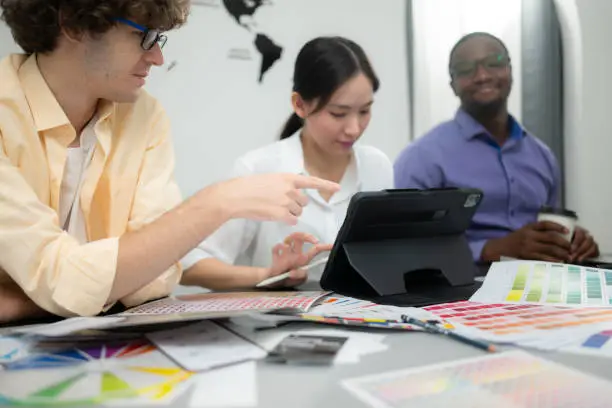 Photo of Multiethnic team of architects and designers are meeting to brainstorm design an application smartphone on a bright modern office working on a laptop.