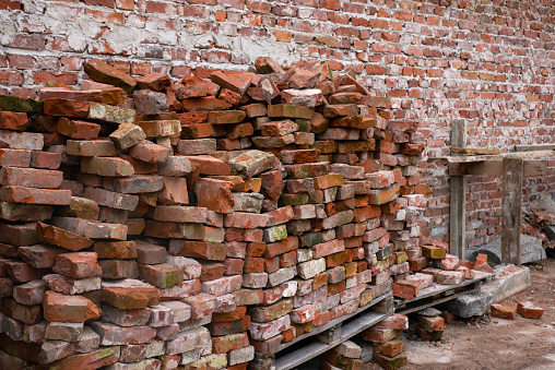 restoration work. the wall of the old building was dismantled. old wet and moldy bricks lie on wooden pallets