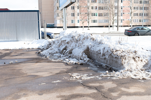 huge snowdrifts and piles of snow on the sidewalk after a heavy April snowfall in the city