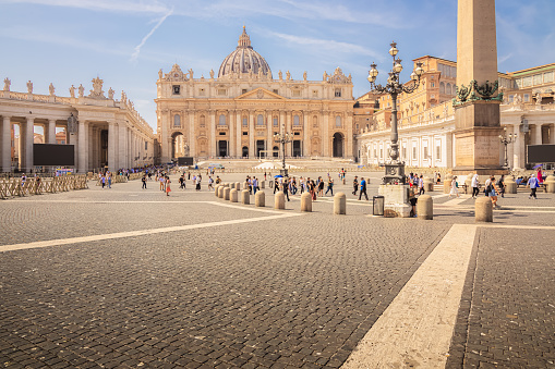 Tourists visit the historic Saint Peter's Square and basilica at the Vatican, home of the Roman Catholic Church, on a sunny summer day in Rome, Italy.