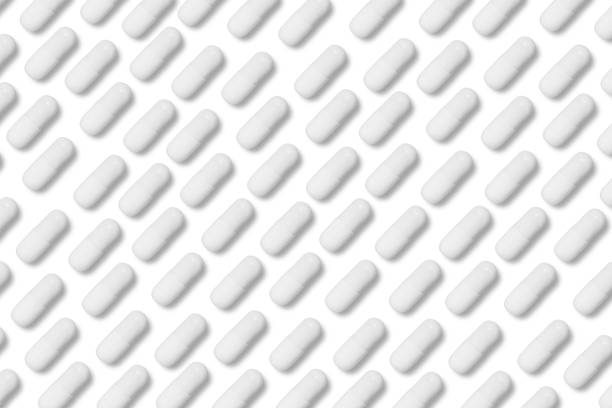 white matte pills or tablets stand in rows on an isolated background