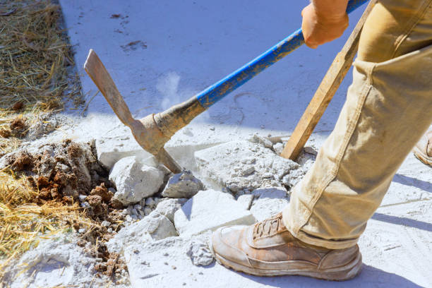 Worker smashes concrete driveway with pickaxe on construction site
