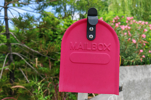 Vintage red mail box at home garden surrounded by green tree