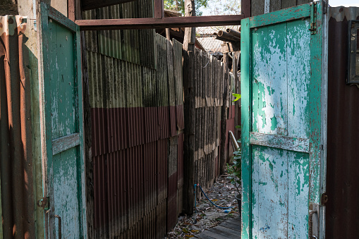 Old wooden door entrance to slum at Thai rural village