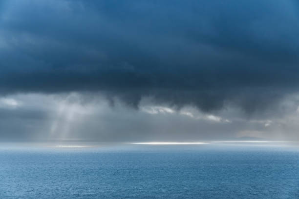 Rain on the sea with stormy clouds and sun rays