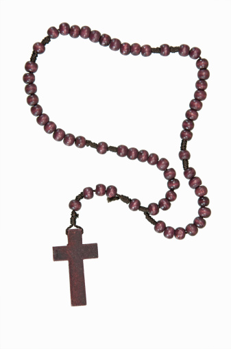 Rosary with white beads laying on a white wood table with a branch with white flower blossoms and green leaves with copy space