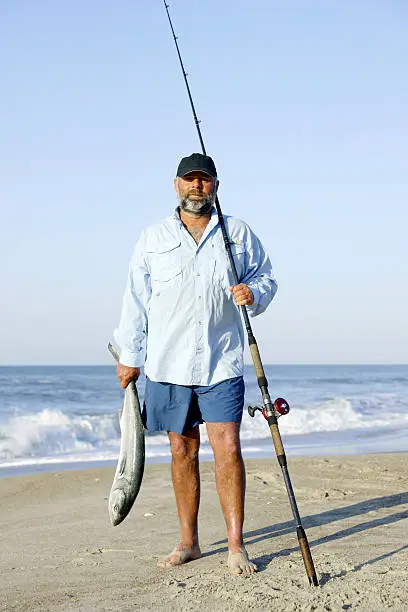 A surf fisherman with a freshly caught bluefish from the surf.
