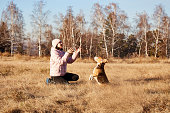 A teenager plays with his dog beagle in an autumn park.