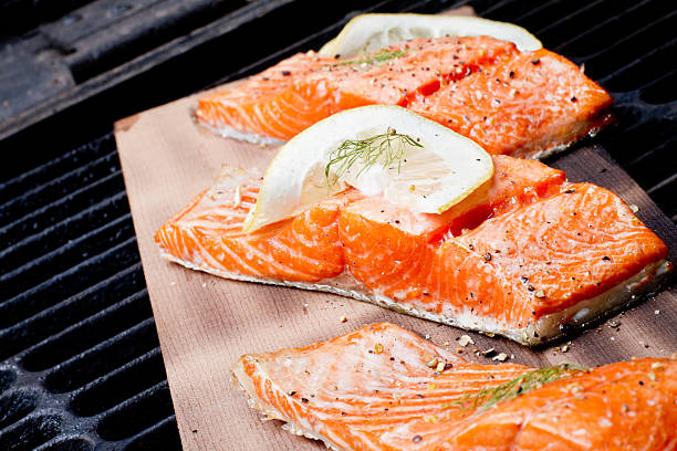 Three Grilled Salmon Filets on Cedar Plank Three wild-caught salmon filets on a cedar plank in a backyard grill.  Fist is bright reddish orange and is topped with lemon, dill and cracked pepper file_thumbview_approve.php?size=1&id=19631280 sockeye salmon filet stock pictures, royalty-free photos & images