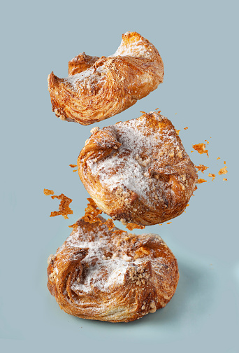 puff pastry buns with crumbs flying over the table, blue background