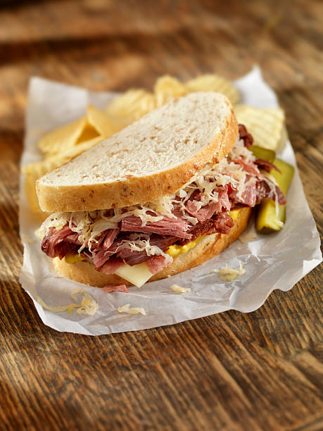 Pastrami Sandwich Pastrami Sandwich on Rye Bread with Swiss Cheese, Sauerkraut, Mustard and a side of Potato Chips-Photographed on Hasselblad H3D2-39mb Camera reuben sandwich stock pictures, royalty-free photos & images