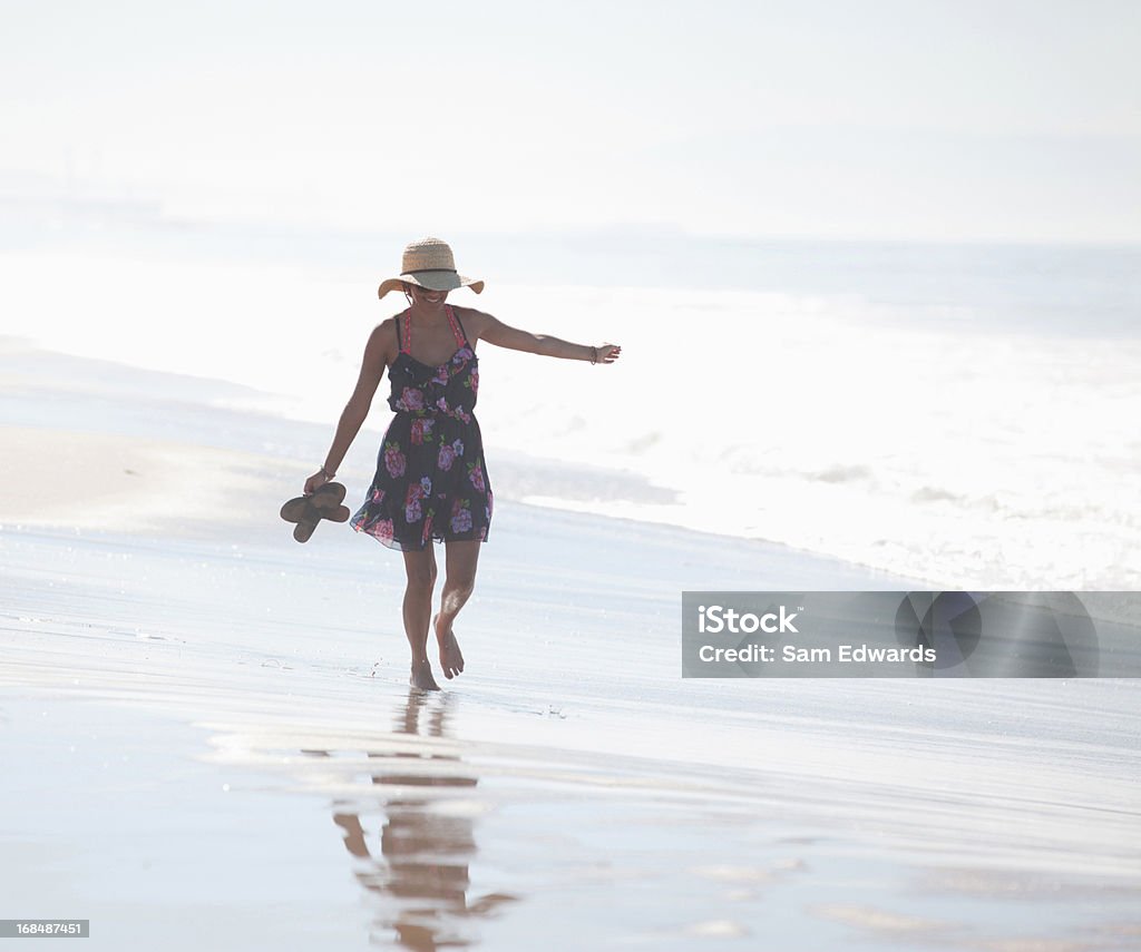 Kobieta przewożących sandały na plaży - Zbiór zdjęć royalty-free (20-24 lata)