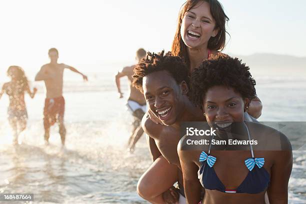 Amigos Jugando En Las Olas En La Playa Foto de stock y más banco de imágenes de 25-29 años - 25-29 años, 30-34 años, Diversión