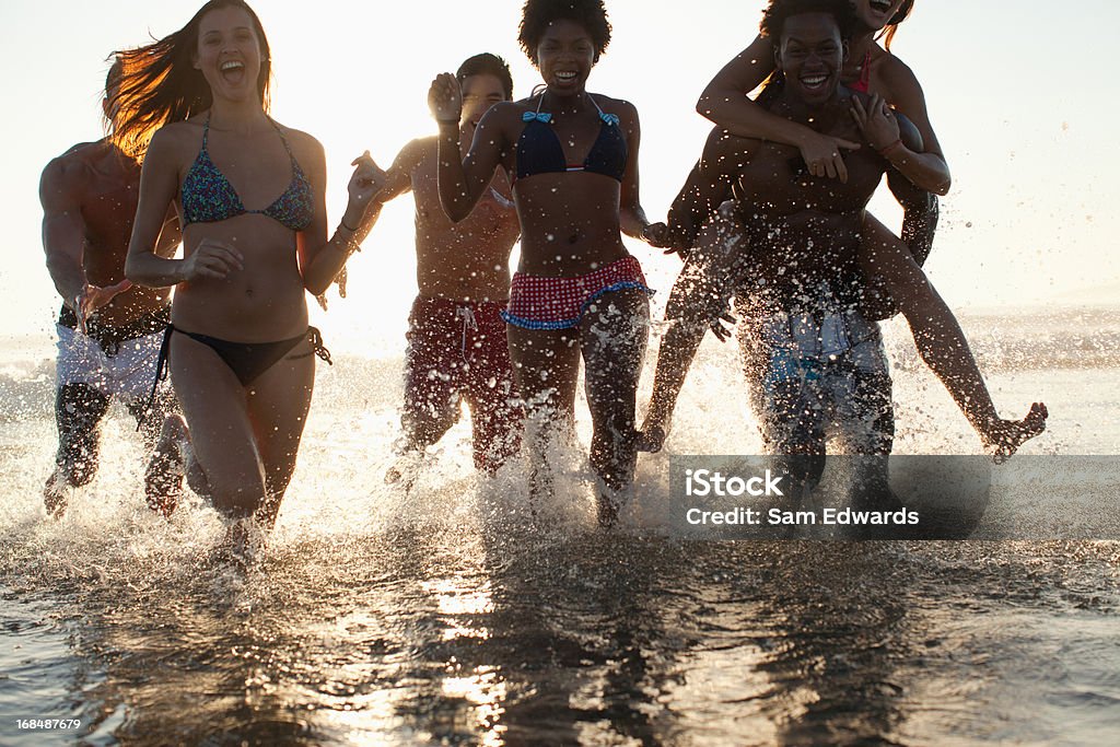 Amis jouant dans les vagues sur la plage - Photo de 20-24 ans libre de droits