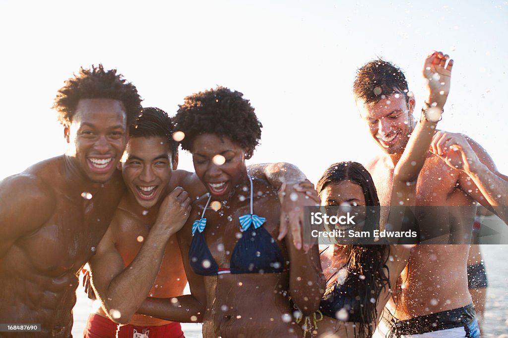 Friends playing in waves on beach - Rojaltivapaa avainsanalla 20−24 vuotta ja tyyppiä Kuvapankin valokuva